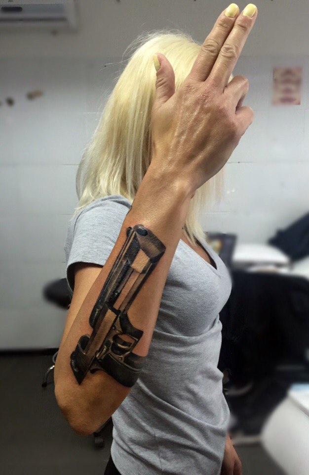Девушка с татуировкой револьверы на пояснице